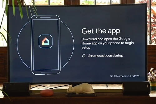 The image shows, on a TV, an invitation to download the Google Home app in your smartphone.
